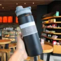 Close-up view of black 18oz vacuum insulated stainless steel water bottle in a cafe - Black