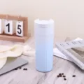 Detailansicht des blau gestreiften Kaffeebechers mit Klappdeckel auf einem Holztisch - 500ml / Verlauf Blau