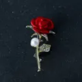 Detailed view of exquisite red rose brooch featuring sparkling rhinestones and elegant gold stem. - Red