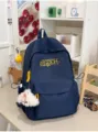 Vista detallada de la mochila estilo universitario azul marino con bordado amarillo y colgante. - Con Colgante / Azul marino