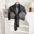 Primo piano dettagliato di uno scialle estivo in maglia grigio scuro e mantella su appendiabiti. - Gilet Senza Maniche / Gilet in lino grigio