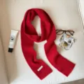 Close up detail of red knit winter scarf, cozy ribbed texture, flat lay aesthetic display. - Red