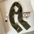 Close-up of dark green knit scarf with cozy texture and stylish flat lay lifestyle props. - Dark Green