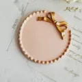 Vassoio per gioielli vintage in resina rosa con fiocco dorato e bordo perlinato - Tondo Rosa