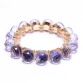 Faceted purple crystal bead bracelet with gold-tone settings and stretch cord design. - Purple