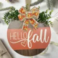 Primo piano dettagliato del cartello in legno autunnale con fiocco di zucca e fogliame verde. - Targa cuore Hello Fall