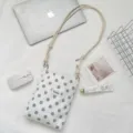 Detail van witte polka dot stoffen crossbody tas met verstelbare touwriem op bureau - Wit Grijs Stippen