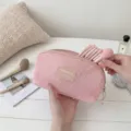 Close-up of a pink mesh makeup bag with cosmetic brushes inside on a white wooden table - L / Pink