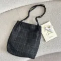 Close-up of vintage dark grey plaid canvas tote bag with drawstring on boucle background. - Drawstring Tote Bag / Thin Strap Woolen Gray