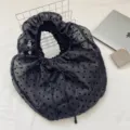 Elegante bolso de mano de organza negra con lunares y un diseño plisado con volantes. - Negro