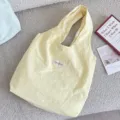 Zitronengelbe Canvas-Tragetasche im Macaron-Stil mit minimalistischen Lifestyle-Requisiten - Leuchtgelb