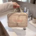 Macro view of a beige mesh travel clothing compression bag being held over a white sink. - M / Beige