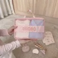 Detailansicht einer rosa Reise-Kleidertasche aus Mesh, die auf einem Teppich gehalten wird. - S / Rosa