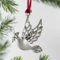 Metal dove Christmas tree ornament with olive branch and red ribbon hanging detail close up - White Dove Bird