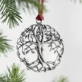 Close-up detail of silver metal tree of life Christmas ornament with red ribbon hanging loop. - Tree of Life