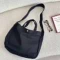 Vista detallada del bolso tote de lona negra con correa ancha para el hombro - Negro