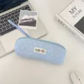 Primo piano di un astuccio azzurro a pois con una simpatica toppa con logo - Blu scuro
