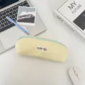 Close-up van een geel polkadot etui met een lichtblauwe rits op een bureau - Teder Geel