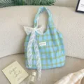 Borsa tote a scacchi azzurro chiaro con grande fiocco di pizzo bianco su divano beige - Borsa Tote a Quadri (Fiocco di Pizzo) / Blu