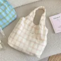 Detaillierte Ansicht einer karierten Stofftasche mit Markenetikett auf beigem Untergrund - Karierte Tragetasche / Weiß