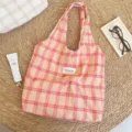Detailansicht der pfirsichfarbenen Plaid-Canvas-Einkaufstasche mit Studio-Label auf Strohmatte - Karierte Tragetasche / Rot