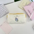 Primer plano de un estuche acolchado blanco con delicado bordado floral morado - Bordado Violeta / 20x7x4,5cm