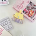 Close-up of a purple and yellow plaid storage bag with a snap closure on a white desk. - Purple Grid