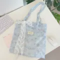 Macro detail of a blue tie-dye floral tote bag with a charming white lace bow accessory. - Shoulder Bag With White Flower