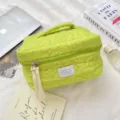 Close-up of lime green quilted floral makeup bag with stylish long ribbon zippers. - Green