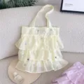Primer plano de un bolso tote de organza amarilla con volantes y bordados florales - Amarillo