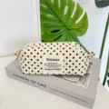 Close-up of cream polka dot canvas pouch showing fabric texture and branding patch - Beige