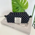 Detailed view of a black and white polka dot canvas pencil case on an aesthetic book prop - Black