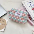 Detailed view of a quilted checkered pouch styled with aesthetic lifestyle props - Slim Style / Orange Grid