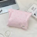 Rosa gestreifte Kosmetiktasche mit Schleifenstickerei in einer Lifestyle-Umgebung - Hellrosa