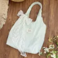 Close-up detail of light blue floral gauze tote bag featuring a large white lace bow - Bag With White Lace Bow Decoration / Light Blue