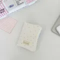 Primo piano di un porta passaporto color crema a pois con bordo a quadretti azzurri - Piccoli pois in lana bianco