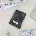 Primo piano del porta passaporto a pois con bordo a quadretti blu su una scrivania. - Denim Strass