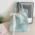 Detailed macro view of the blue floral tote bag featuring an elegant white lace bow charm - With White Flower Accessory / Misty Blue Floral