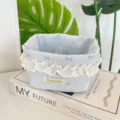 Gros plan d'un panier de rangement en tissu bleu avec dentelle et motif de nœuds décoratifs. - Bleu Glacé