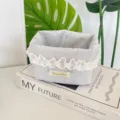 Détail d'un panier de rangement en tissu avec dentelle délicate et motifs de nœuds bleus - Gris clair