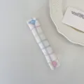 Dettaglio dell'organizzatore per cavi in tessuto a quadretti macaron con bottone a cuore - Quadretti Colorati Dopamina
