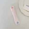 Dettaglio del ferma cavi rosa floreale con bottone a cuore su un piatto decorativo. - Puntini Floreali Rosa