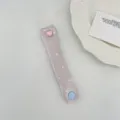 Primo piano di un morbido organizzatore per cavi a pois con bottone a cuore rosa. - Raso Lavanda a Pois