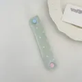 Vista dall'alto del passacavo a pois verde macaron con un simpatico bottone a cuore blu. - Raso Verde Chiaro a Pois