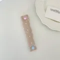 Primo piano dell'organizer per cavi con bottone a pressione cuore e motivo a pois - Raso Rosa Polvere a Pois