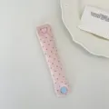 Dettaglio di un ferma cavo in tessuto a pois rosa con bottone a pressione a cuore - Rosa Chiaro a Pois