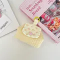 Close-up of quilted floral coin purse with pink snap button and yellow ring clip - Bright yellow