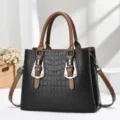 Detailed view of crocodile embossed pattern on a black and brown women's handbag. - Black