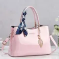 Elegante borsa a mano in vernice rosa con sciarpa di seta e ciondolo a foglia oro. - Rosa