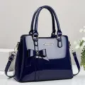 Elegant navy blue patent leather handbag with a stylish bow detail and gold-tone hardware - Blue